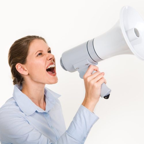 Portrait of businesswoman holding megaphone shouting something on a white background